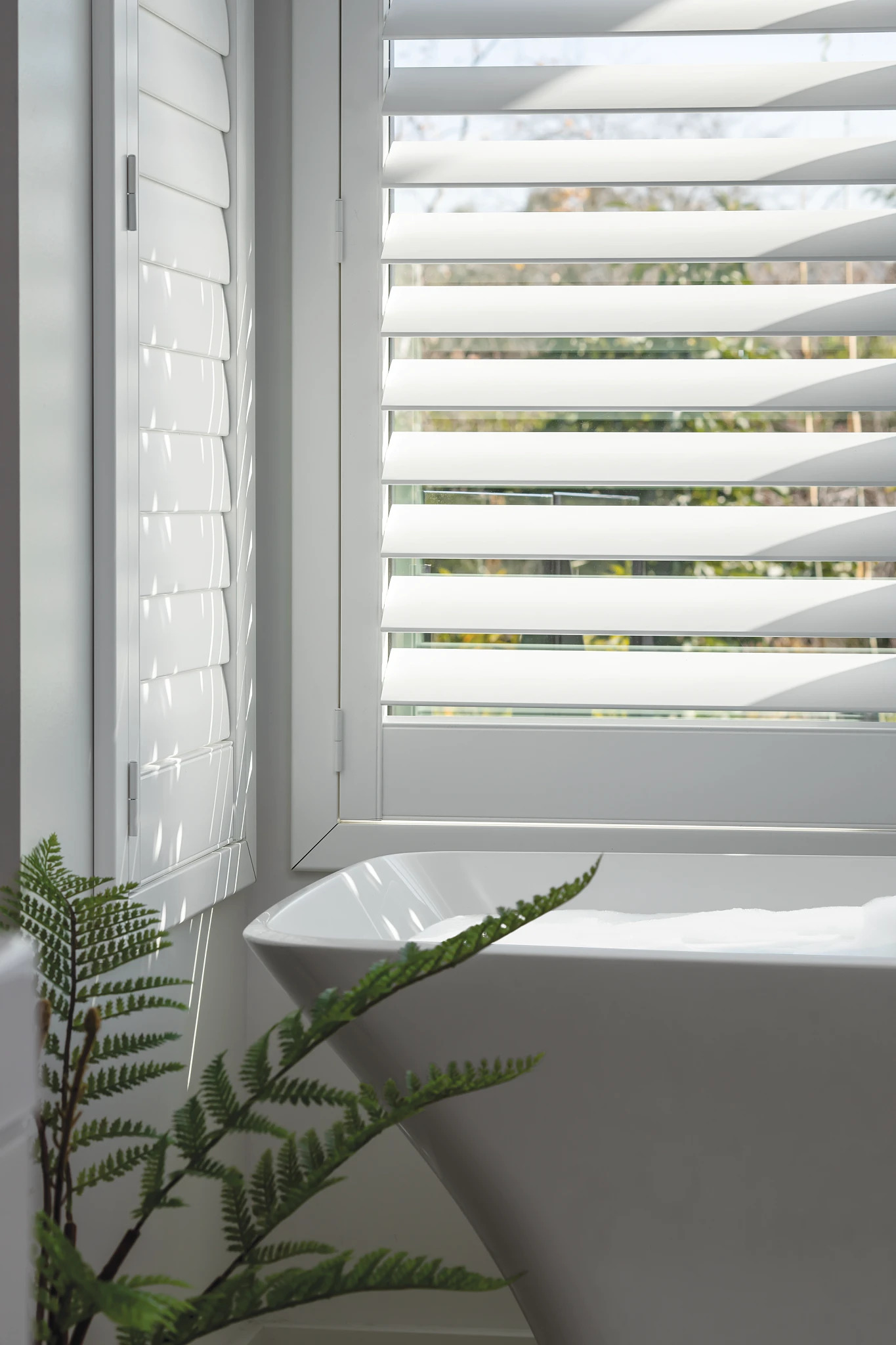 Coastal-style white window shutters in a bright room