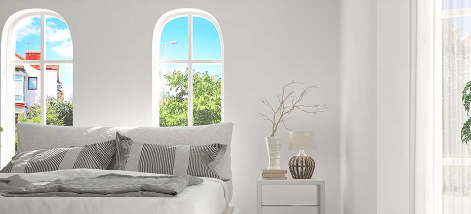 Shutters are great for Specialty Shapes! Room with bare arched windows and a bed with grey bedspread